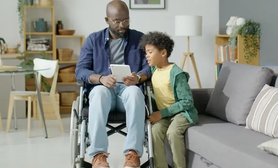 man in wheelchair and child looking at tablet