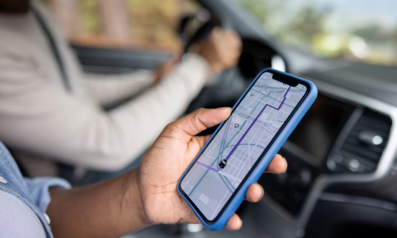 Close-up on an African American couple using the GPS on a cell phone while driving a car - lifestyle concept. **DESIGN ON SCREEN WAS MADE FROM SCRATCH BY US**