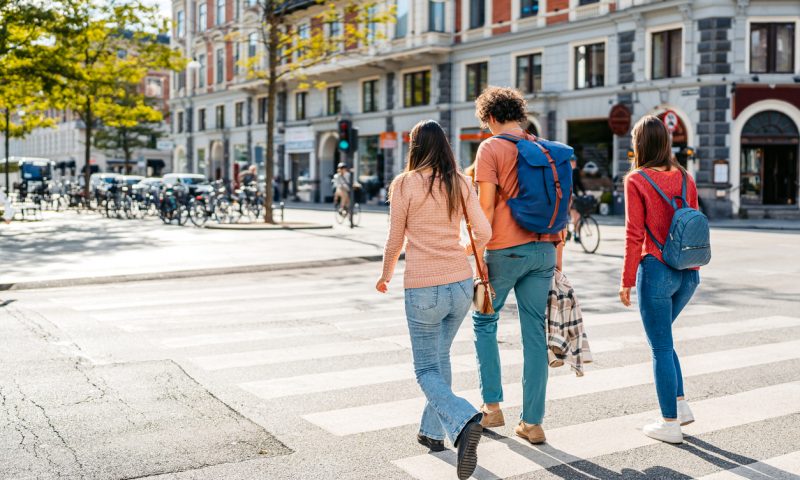 Three young friends crossing the street in Copenhagen in Denmark.