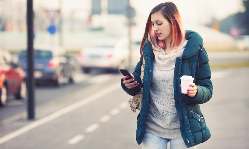 Teenager text messaging while walking on the city street